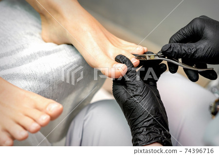Pedicure master is cutting cuticle 74396716