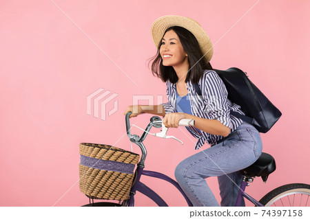 Charming asian woman riding bicycle with wicker basket Charming asian woman riding bicycle with wicker basket 74397158