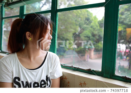 Beautiful chinese Girl waiting someone so long and feeling bad, She rested her chin on her hand in hong kong china 74397718