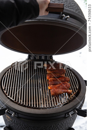 Winter bbq in the fresh white snow, Men grilling chicken wings in the winter onn grill 74398633