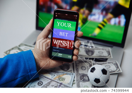 Lucky winner at football betting with phone in hand and dollar bills. Betting and gambling concept Lucky winner at football betting with phone in hand and dollar bills. Betting and gambling concept 74399944