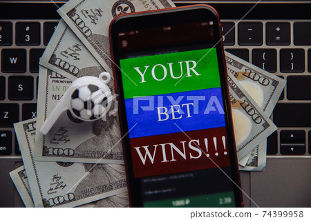 Smartphone with online gambling application, dollar bills and soccer ball on a laptop. Betting online concept. Close-up Smartphone with online gambling application, dollar bills and soccer ball on a laptop. Betting online concept. Close-up 74399958
