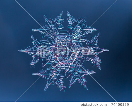 Snowflake on smooth gradient background. Macro photo of real snow crystal on glass surface. This is small snowflake with unusual pattern. 74400359