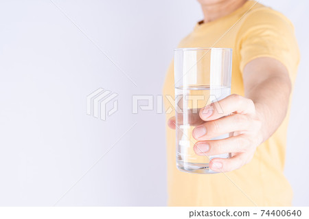 Man holding glass of water isolated grey background. Clean drinking water in clear glass. 74400640