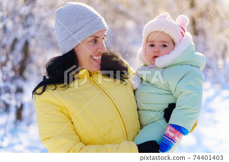 family portrait in the winter forest, mother and child, bright sunlight and shadows on the snow, beautiful nature 74401403
