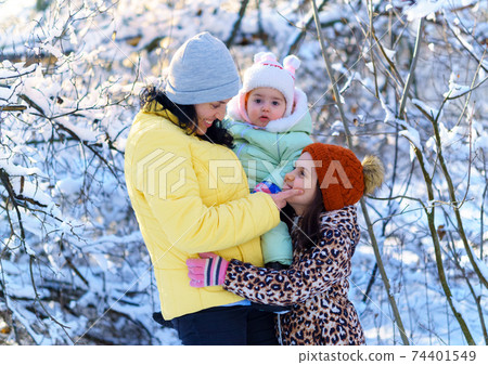 family portrait in the winter forest, mother and children, bright sunlight and shadows on the snow, beautiful nature 74401549