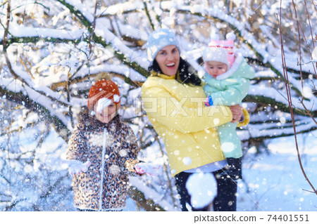family throwing snow in the winter forest, mother and children, bright sunlight and shadows on the snow, beautiful nature family throwing snow in the winter forest, mother and children, bright sunlight and shadows on the snow, beautiful nature 74401551