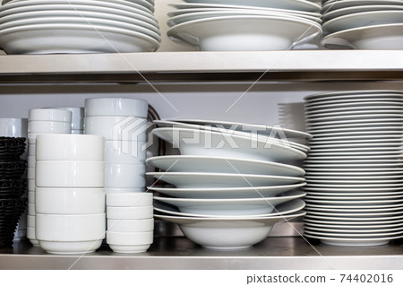 White plates and bowls in the kitchen shelf at the restaurant 74402016