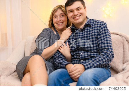 portrait of adult couple sitting on a sofa at home portrait of adult couple sitting on a sofa at home 74402925