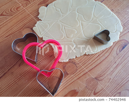 Heart shaped cookie cutter with cut hearts. Wooden rustic background, Valentine's Day, greeting card, pastry, Copy space, top view, love concept, Engagement, love, marriage 74402946