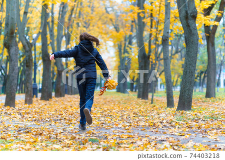 a girl running through the park and enjoys autumn, beautiful nature with yellow leaves a girl running through the park and enjoys autumn, beautiful nature with yellow leaves 74403218