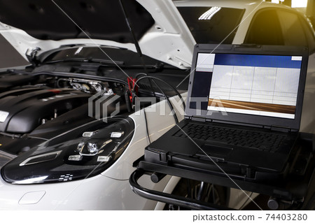 Mechanic use laptop near car engine. Modern car diagnostic program on screen. Car service concept. Mechanic use laptop near car engine. Modern car diagnostic program on screen. Car service concept. 74403280
