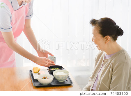 Young caregiver serving tea Young caregiver serving tea 74403500
