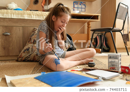 girl draws at home, artistic creation, makes creative artwork from paper, paints and brushes girl draws at home, artistic creation, makes creative artwork from paper, paints and brushes 74403711