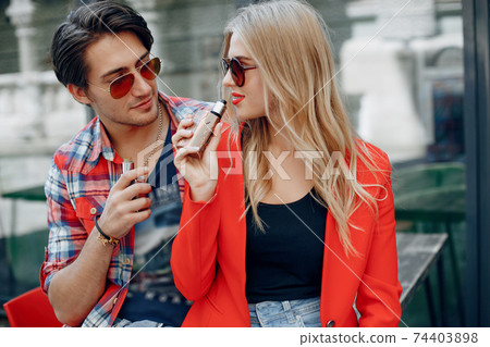 Stylish young couple with vape in a city Stylish young couple with vape in a city 74403898