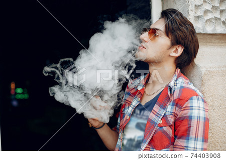 Stylish and elegant man in a city with vape 74403908