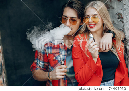 Stylish young couple with vape in a city 74403910