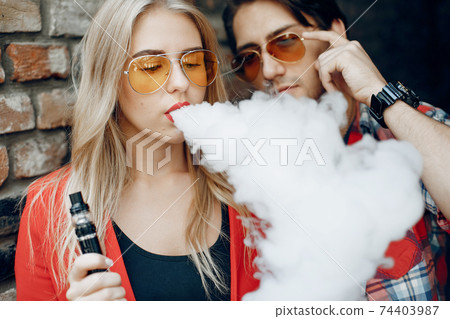 Stylish young couple with vape in a city 74403987
