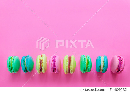 Sweet almond colorful pink blue yellow green macaron or macaroon dessert cake isolated on trendy pink pastel background. French sweet cookie. Minimal food bakery concept. Flat lay top view, copy space 74404082