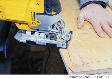 young man carpenter builder working with electric jigsaw and wood. young man carpenter builder working with electric jigsaw and wood. 74404954