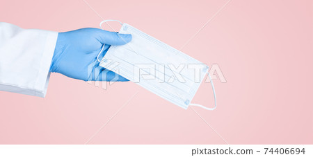 Hand in medical gloves hold medical protective mask. 74406694
