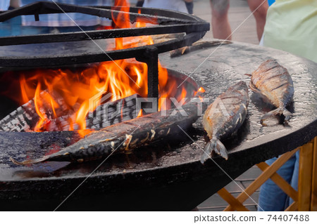Process of grilling mackerel fish on black brazier with hot flame: close up 74407488