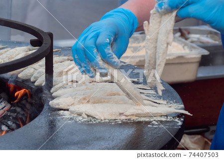 Chef cooking european smelt fish in flour on black at food festival - side view 74407503
