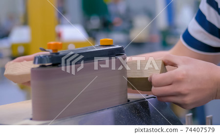 Man carpenter using belt sander machine, polishing wood product: close up 74407579