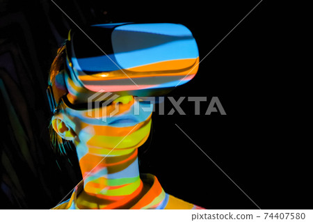 Young woman using virtual reality headset at dark interactive VR exhibition 74407580