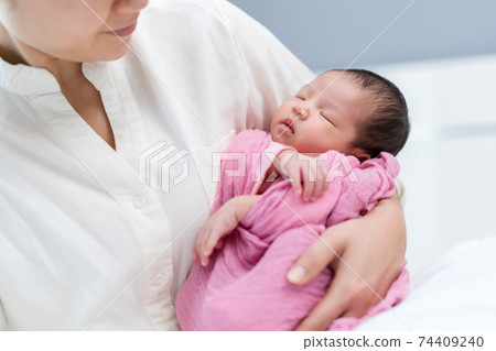 mother holding newborn baby sleeping in arm mother holding newborn baby sleeping in arm 74409240