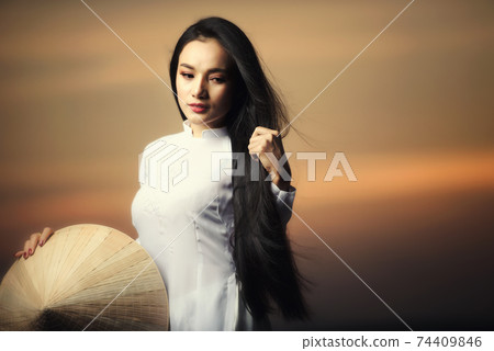 Portrait of Beautiful Asian girls with Ao Dai vietnam traditional dress on Sunset landscapes Portrait of Beautiful Asian girls with Ao Dai vietnam traditional dress on Sunset landscapes 74409846