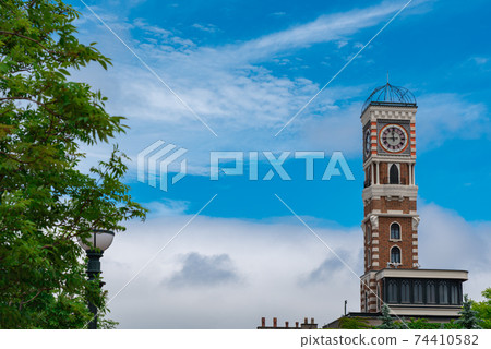 Clock tower in a green and blue landscape 74410582