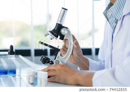 Scientist wear lab coat and protective wear are working with research or doing investigations with test tubes in experiment, Laboratory and development concept 74412835
