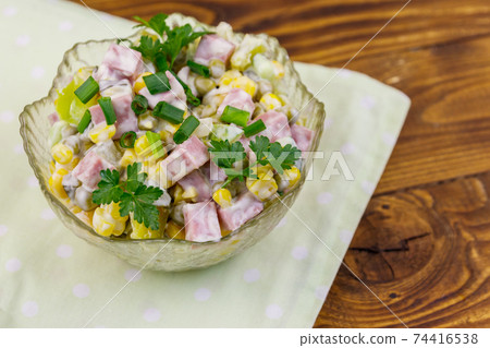 Tasty salad with sausage, green pea, canned corn, bell pepper, cucumber and mayonnaise on wooden table 74416538