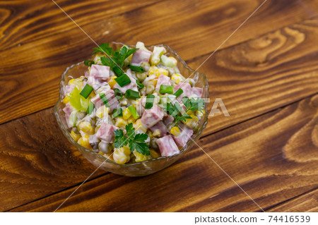 Tasty salad with sausage, green pea, canned corn, bell pepper, cucumber and mayonnaise on wooden table 74416539