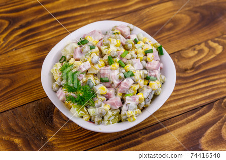 Tasty salad with sausage, green pea, canned corn, bell pepper, cucumber and mayonnaise on wooden table. Top view Tasty salad with sausage, green pea, canned corn, bell pepper, cucumber and mayonnaise on wooden table. Top view 74416540