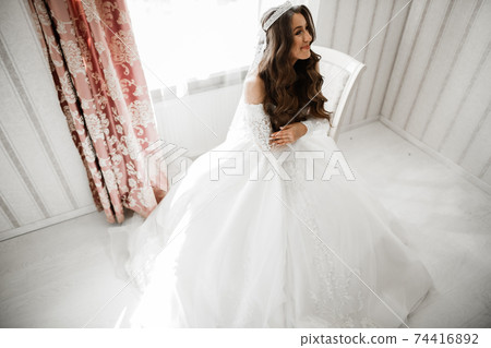 Beautiful bride wearing fashion wedding dress with feathers with luxury delight make-up and hairstyle, studio indoor photo shoot 74416892