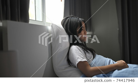 A little sick girl covered in a blanket is lying on the bed and measuring the temperature. A little sick girl covered in a blanket is lying on the bed and measuring the temperature. 74417946