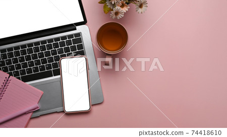 Overhead shot of feminine workspace with smart phone, laptop, notebook and copy space on pink background. Overhead shot of feminine workspace with smart phone, laptop, notebook and copy space on pink background. 74418610