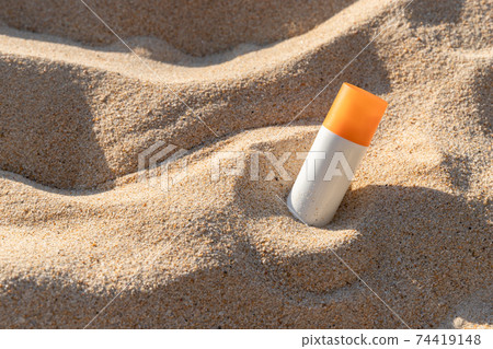 Bottle of sunscreen lotion on the beach by the sea Bottle of sunscreen lotion on the beach by the sea 74419148