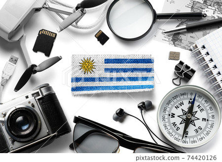 Flag of Uruguay and travel accessories on a white background. 74420126
