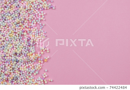 Small colorful pastel balls in a border on pink paper 74422484