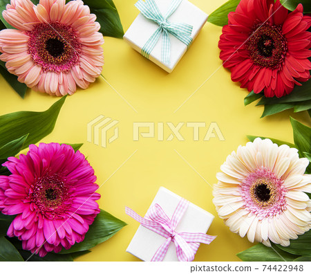Gerbera flowers and gift boxes on a yellow 74422948