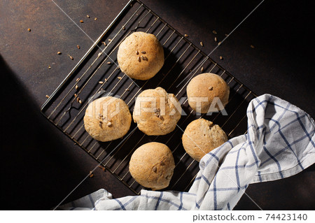 Homemade wholemeal rye wheat buns with seeds on wooden table, dark rustic background. 74423140