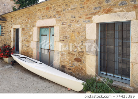 Greek stone house village style with a kayak in front Greek stone house village style with a kayak in front 74425389