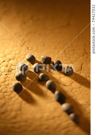 Arrow made of small pebbles on cracked ocher Arrow made of small pebbles on cracked ocher 74427032