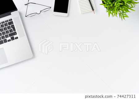 Overhead shot of laptop and business accessories on white background with copyspace. Office desktop.  Flat lay 74427311