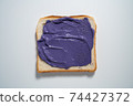 spreading Purple paste on a toast on white Background. Top view 74427372