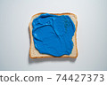 spreading Dark Blue paste on a toast on white Background. Top view 74427373