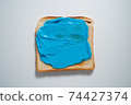 spreading Blue paste on a toast on white Background. Top view 74427374